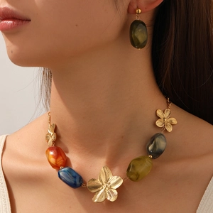 Gros plan détaillé sur le pendentif fleur dorée et le collier de perles en résine colorée