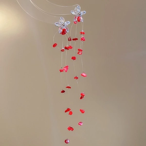 Detail of bohemian tassel earrings with clear flower charms and red stone accents