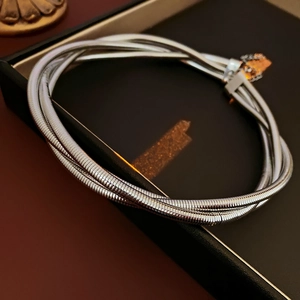 Détail d'un bracelet serpent argenté multicouche dans un écrin à bijoux noir chic
