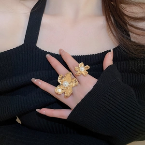 Detailed macro view of irregular gold flower rings with pearls on elegant female model
