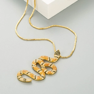 Macro shot of gold snake pendant necklace with multi-color zircon inlay on minimalist stand