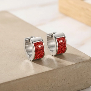 Close-up of silver hoop earrings paved with vibrant red crystals on industrial base