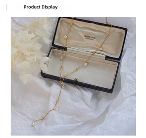 Detailed close-up of a gold-plated Y-shaped necklace with elegant white pearls in a box