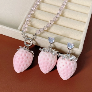 Macro detail of pink strawberry pendant jewelry set with beads and cubic zirconia