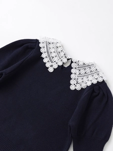 Close-up of navy knit top with white crochet lace Peter Pan collar and pearl back button