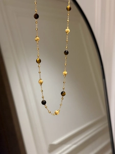 Détail d'une chaîne plaquée or 18k avec perles œil de tigre et sphères dorées mates