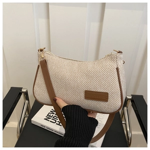 Detail of beige herringbone woven texture and brown leather trim on the shoulder bag