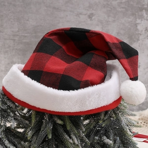Detail der rot-schwarz karierten Weihnachtsmütze mit Plüschrand auf gefrostetem Kiefernzweig
