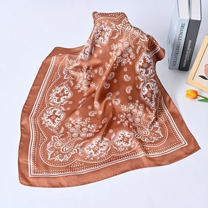 Close-up of brown silk scarf with white paisley patterns artfully folded on white table