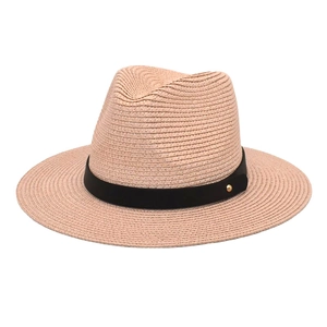Detail of pink paper straw hat with black ribbon and golden rivet accent for sun protection