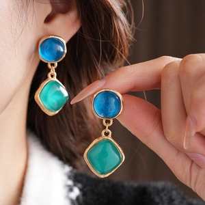 Détail de boucles d'oreilles vintage dorées avec pierres bleues et vertes