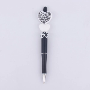 Detail of DIY beaded pen featuring a white floral heart and cow print beads