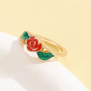 Bague dorée de luxe avec rose émaillée rouge et feuilles vertes sur support en pierre