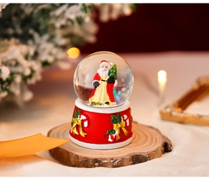 Detailed view of a Christmas snow globe with a Santa figure and red embossed base