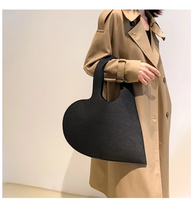 Street style shot of a trendy heart-shaped black felt handbag with cutout handle detail