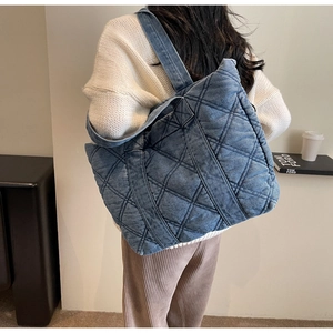 Détail d'un grand sac cabas en denim matelassé bleu avec coutures en losange et sangle