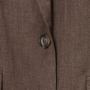 Gros plan détaillé du bouton à texture marbrée sur un blazer marron foncé