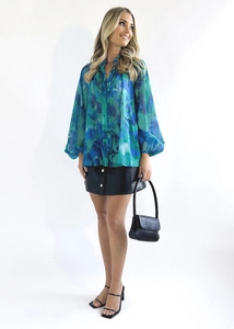 Vue complète d'une chemise imprimée à col en V pour femme avec jupe en cuir et talons