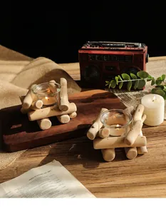 Detalle de dos portavelas de madera flotante con vasos en una mesa rústica