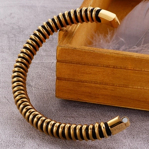 Detail of gold spiral men's leather bracelet with magnetic clasp on a wood box