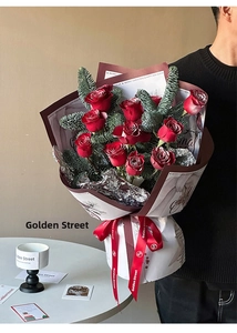 Close-up of Christmas bouquet with red roses and pine branches in festive wrapping