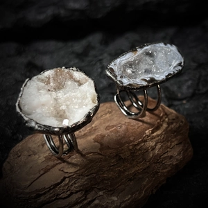 Close-up of two handmade raw geode crystal rings on rustic bark with antique silver bands