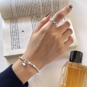 Detail of 925 sterling silver beaded bracelet with heart pendant on an open book