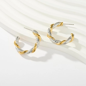 Close-up of gold and silver mixed color twisted texture C-shape earrings on wavy tray