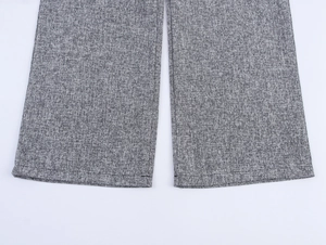 Close-up detail of grey tweed fabric texture and hem stitching on straight-leg trousers