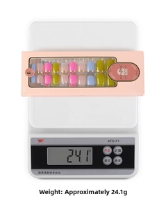 Close-up of boxed French press-on nails with multi-color tips and gold line accents