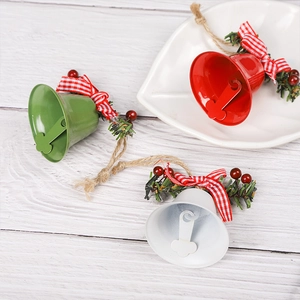 Three festive metal Christmas bells in red, green, and white with bows on wood background