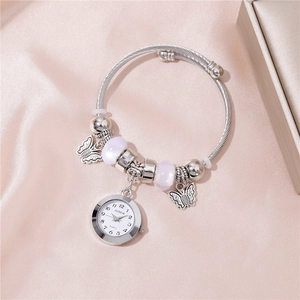 Vue macro d'une montre bracelet à perles argentées avec pendentif papillon et perles mauves