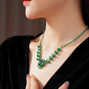 Detailed close-up of a silver-toned necklace with marquise and pear-cut green gemstones