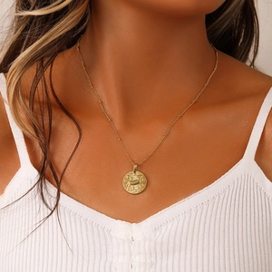 Detailed close-up of a golden coin pendant featuring an embossed deer and star motif