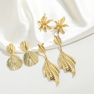 Three gold vintage earrings set with petal and leaf designs on white silk background