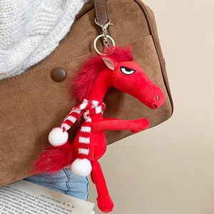 Detail of red flocked pony charm with striped scarf hanging on a brown suede bag
