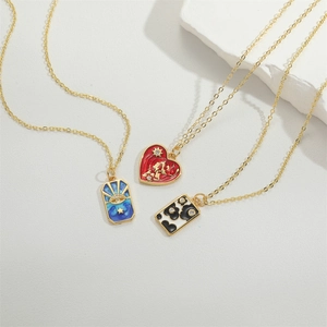 Three enamel star and heart pendants on gold chains over a white stone surface