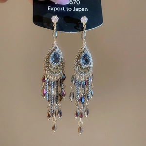 Detail of luxury drop earrings with blue teardrop crystals and sparkling metallic tassels