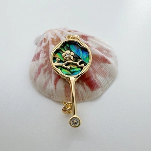 Macro detail of 18K gold-plated rose key pendant with natural abalone shell inlay