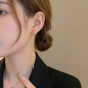 Boucles d'oreilles nœud dorées avec longues franges en chaîne serpent sur un mannequin