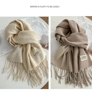 Detail of soft cream and taupe winter scarves with tassels and premium woven brand labels