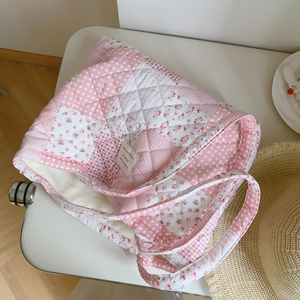 Detailed macro view of quilted floral fabric texture and chic French label on pink tote bag