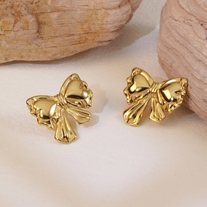 Elegant gold bow earrings on natural stone background with metallic polished finish