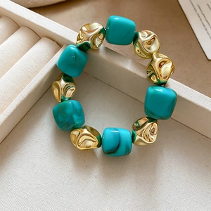 Close-up of marble texture square beads and irregular golden metal beads on a bracelet