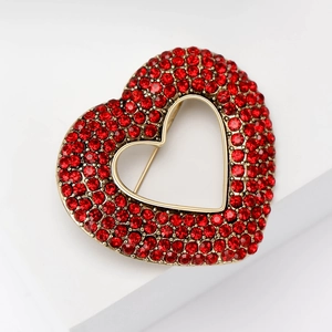 Detail of a vintage heart brooch with red rhinestones set in a golden metal frame