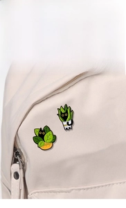 Detailed view of two cute black cat enamel pins pinned on a beige canvas tote bag