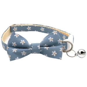 Detail of light blue floral pet collar with bowtie, silver bell and white safety buckle