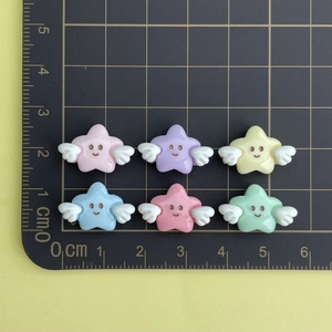 Macro view of colorful resin star charms with wings on a measurement mat