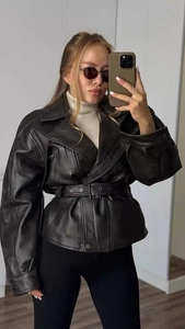 Close-up of black faux leather motorcycle jacket detailing texture and metal zipper hardware