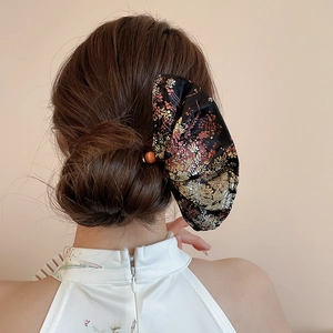 Detail of embroidered floral hair stick on elegant bun with traditional silk texture